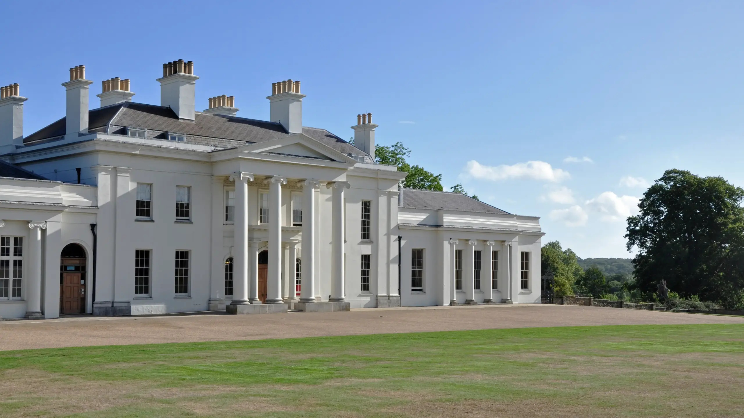 White country house with classical columns and landscaped grounds